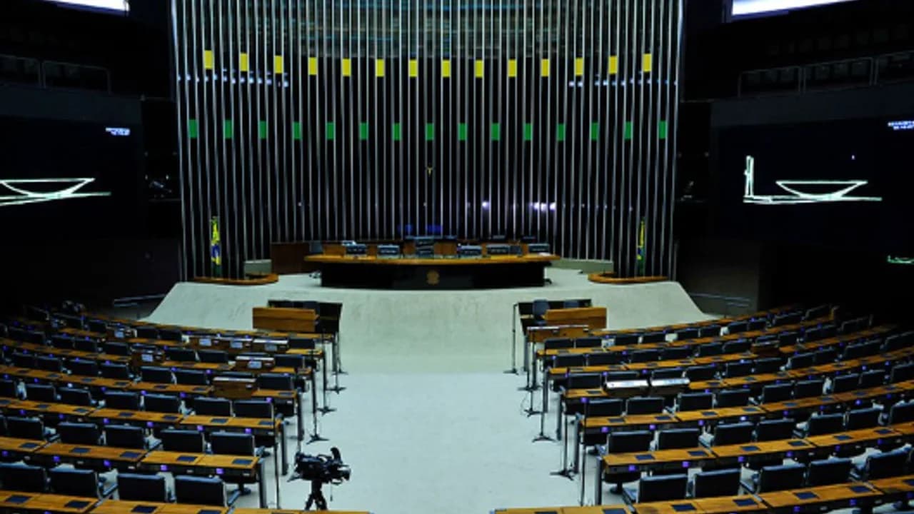 Foto de plenário legislativo brasileiro com arquitetura inspirada em Brasília e mesas de debate público
